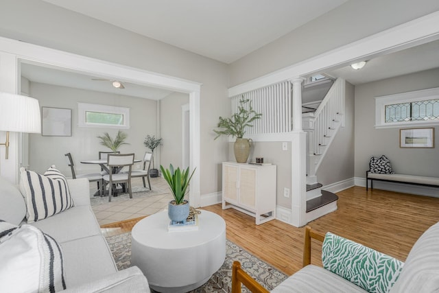 living area featuring plenty of natural light, stairway, light wood-style flooring, and baseboards