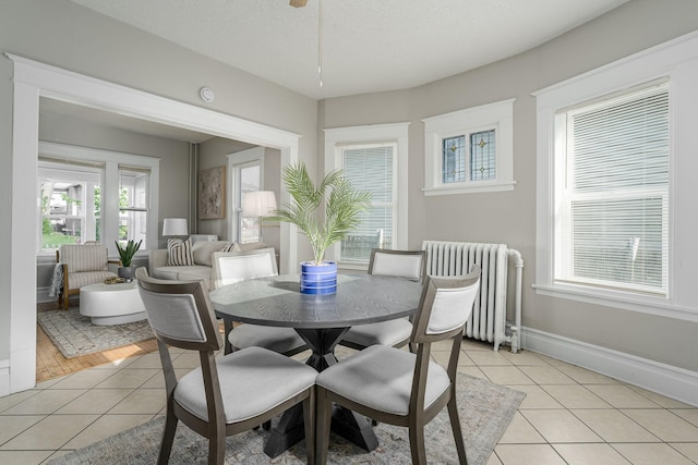 dining space featuring radiator, light tile patterned floors, plenty of natural light, and baseboards