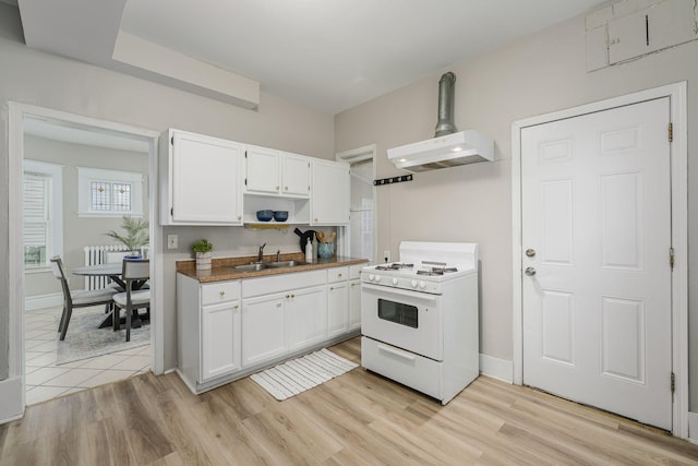 kitchen featuring white range with gas stovetop, a sink, white cabinets, and light wood-type flooring