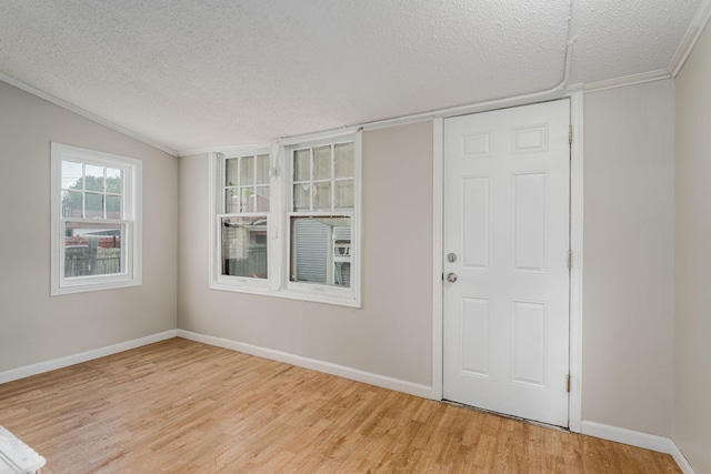 entrance foyer featuring light wood-style flooring, a textured ceiling, baseboards, and ornamental molding