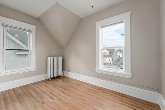 bonus room featuring radiator, light wood finished floors, lofted ceiling, and baseboards