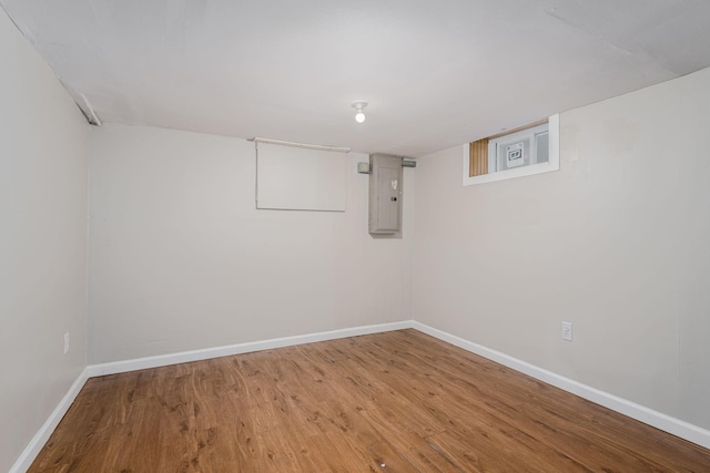finished below grade area with electric panel, baseboards, and wood finished floors