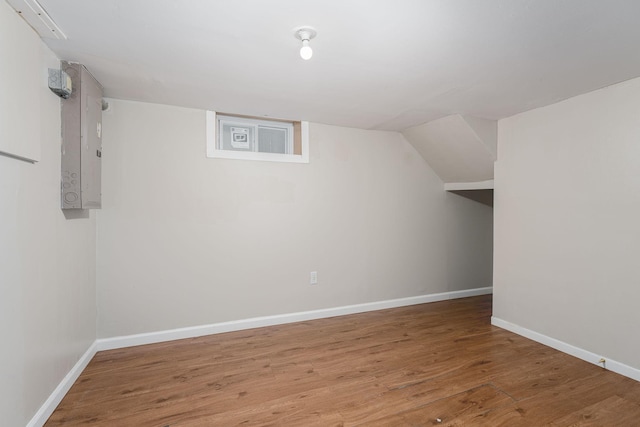 additional living space featuring wood finished floors, baseboards, and electric panel