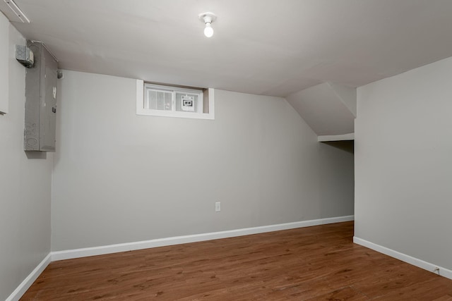 additional living space with wood finished floors, electric panel, and baseboards