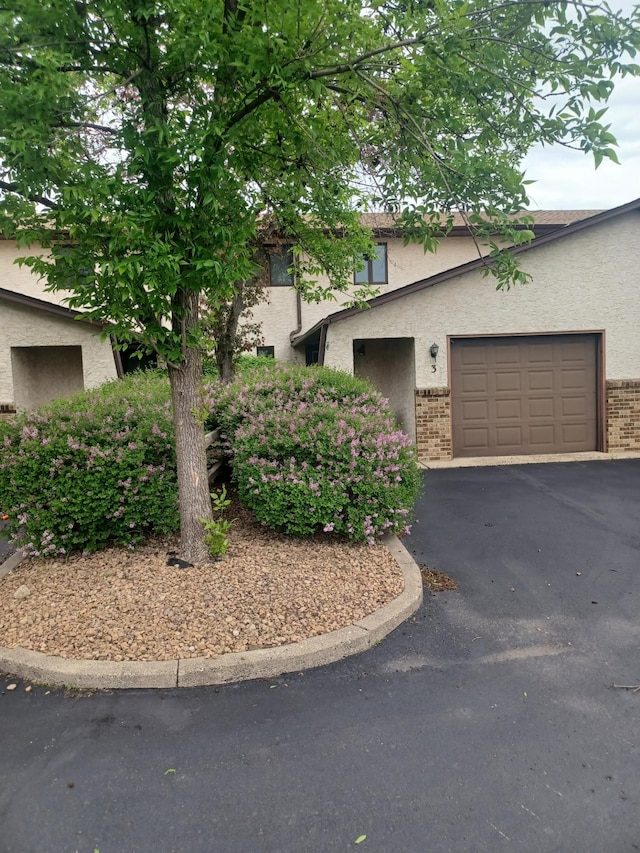 149 Riverview Dr Unit 5, Monticello, MN 55362 - obstructed view of property featuring stucco siding, driveway, a garage, and brick siding