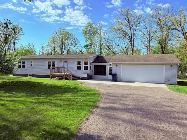 view of front of house featuring an attached garage, asphalt driveway, and a front lawn