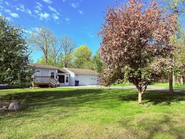 single story home featuring a front lawn, a deck, and an attached garage