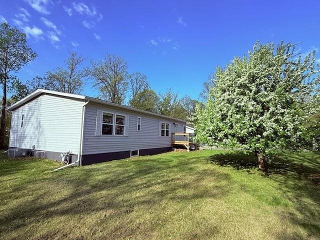 rear view of house featuring a lawn and a wooden deck