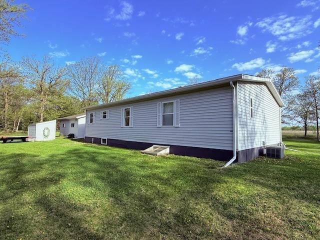 rear view of property featuring a lawn and central air condition unit