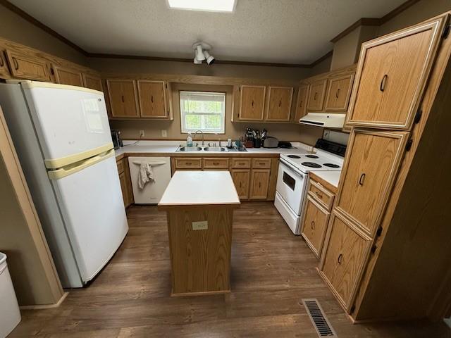 kitchen featuring white appliances, ventilation hood, crown molding, a center island, and light countertops