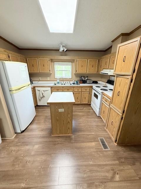 kitchen with white appliances, exhaust hood, ornamental molding, light brown cabinetry, and light countertops