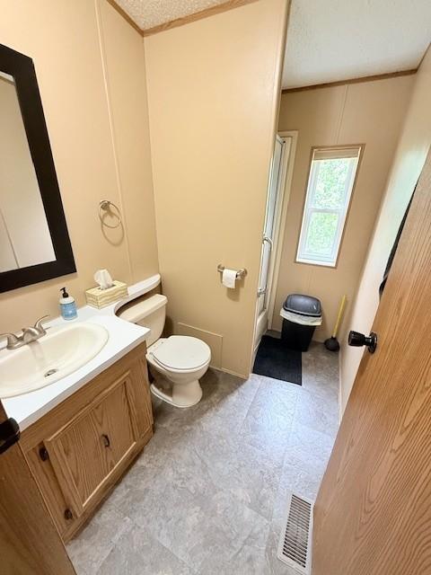 bathroom with toilet, vanity, crown molding, and tile patterned floors