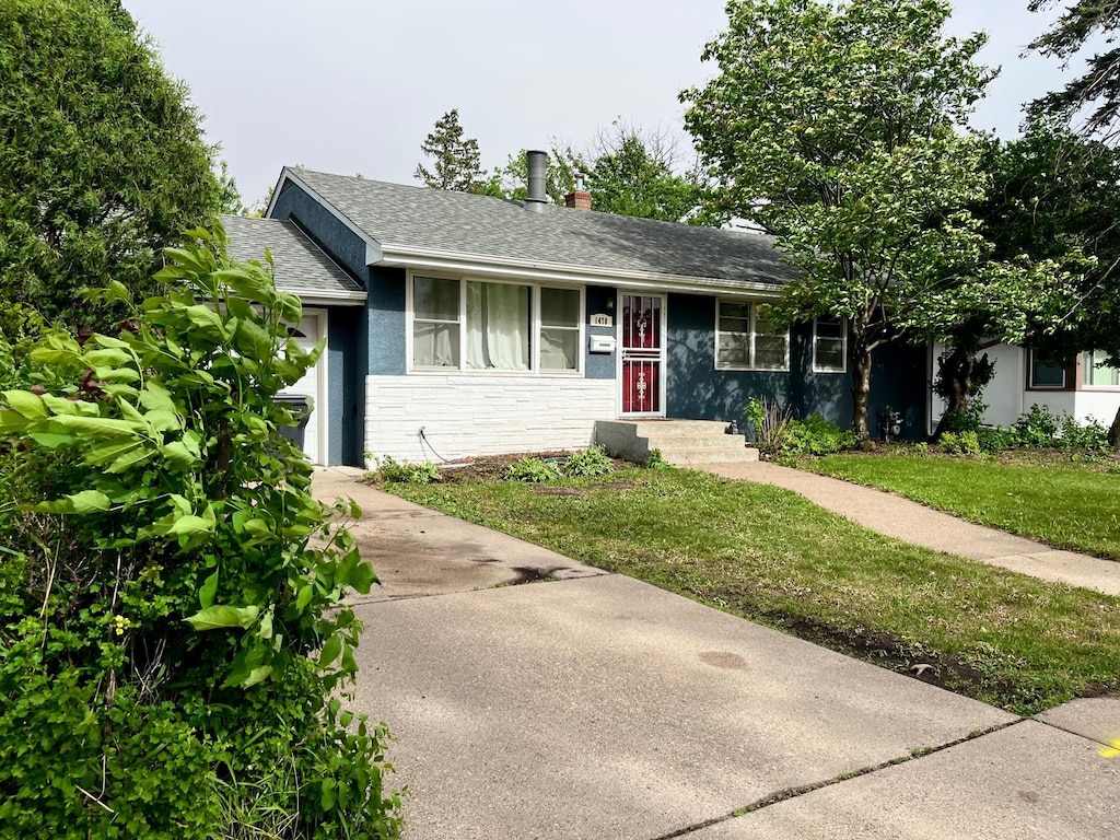 1478 Birmingham St, Saint Paul, MN 55106 - ranch-style house with roof with shingles, concrete driveway, a front yard, stucco siding, and stone siding