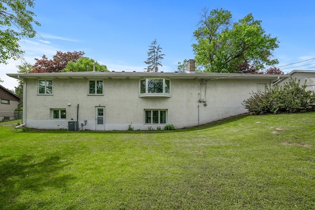 1213 Highview Dr, New Brighton, MN 55112 - rear view of house with stucco siding, a lawn, a chimney, and central AC