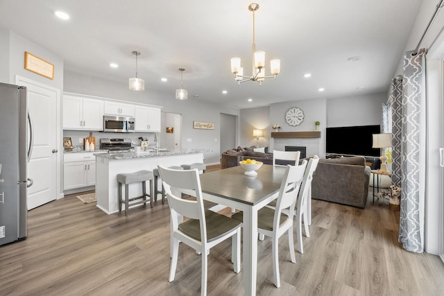 8857 152nd Ln NW, Ramsey, MN 55303 - dining space featuring recessed lighting, light wood-style floors, a fireplace, and a chandelier