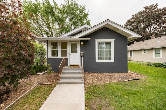 bungalow featuring a front yard and stucco siding