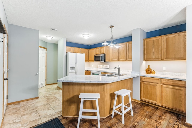 10938 181st Ln NW, Elk River, MN 55330 - kitchen with white appliances, a sink, light countertops, a kitchen bar, and a textured ceiling