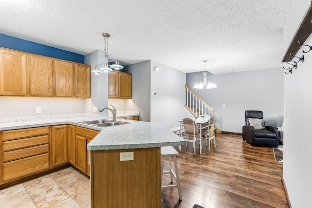 10938 181st Ln NW, Elk River, MN 55330 - kitchen featuring a sink, a chandelier, a peninsula, a textured ceiling, and light countertops