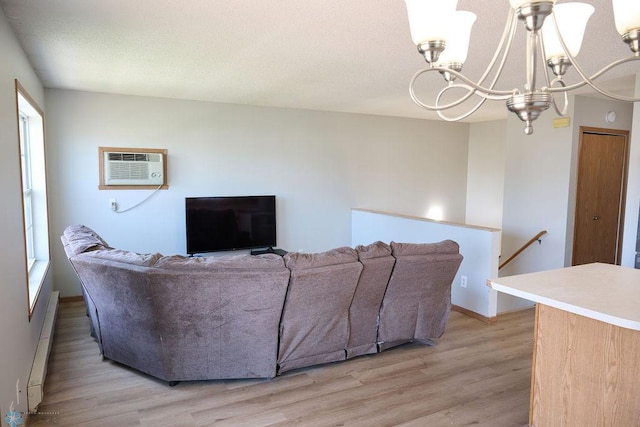 living area with baseboard heating, a chandelier, light wood-type flooring, and a wall mounted AC