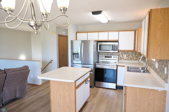 kitchen featuring appliances with stainless steel finishes, a sink, light countertops, and light wood-style flooring