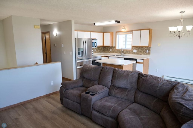 living room featuring wood finished floors, a chandelier, a textured ceiling, and a baseboard heating unit