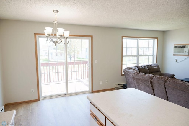 dining space with a chandelier, light wood-type flooring, a textured ceiling, a wall mounted air conditioner, and baseboards
