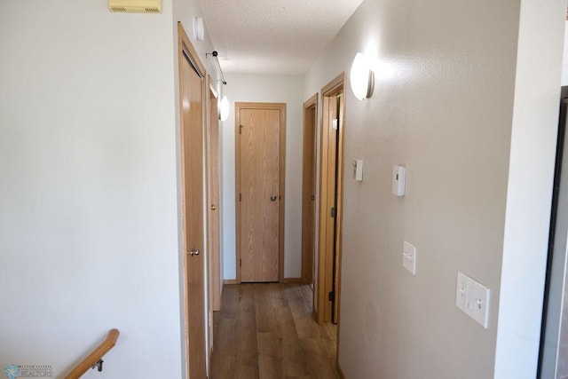 hall with wood finished floors and a textured ceiling