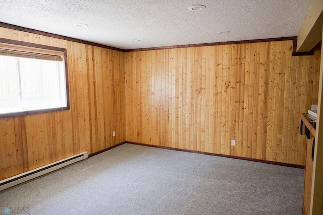 unfurnished room with a baseboard heating unit, wooden walls, a textured ceiling, and carpet floors