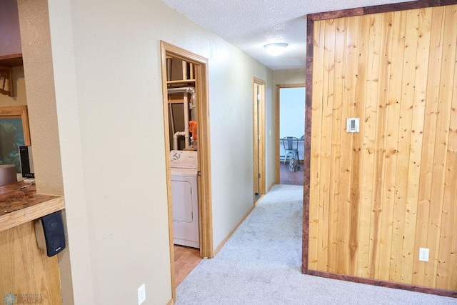 hall featuring washer / dryer, carpet floors, and a textured ceiling