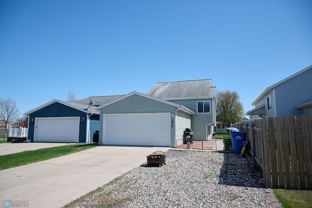 view of front of house with fence, a garage, concrete driveway, and a fire pit