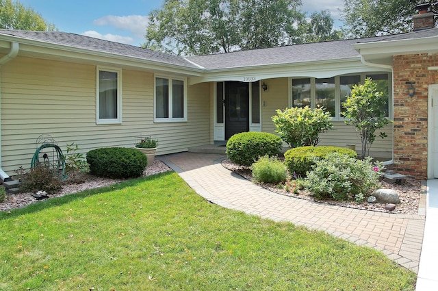 property entrance featuring a yard and roof with shingles