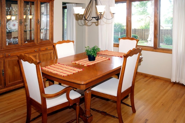 dining space featuring a chandelier, healthy amount of natural light, light wood-style floors, and baseboards