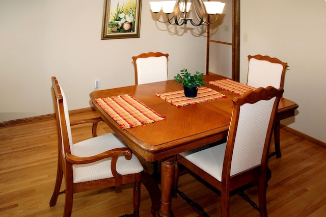 dining area with a chandelier, wood finished floors, and baseboards