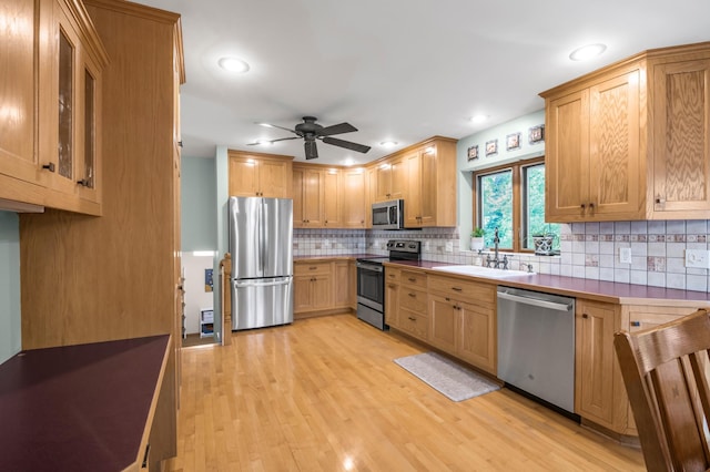 7712 Bester Ave, Inver Grove Heights, MN 55076 - kitchen with stainless steel appliances, a ceiling fan, a sink, decorative backsplash, and light wood-style floors