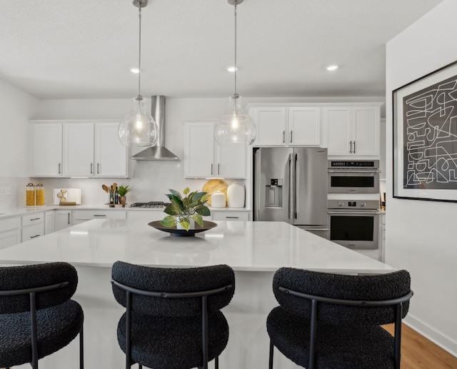 1684 Upper 143rd St E, Rosemount, MN 55068 - kitchen featuring wall chimney exhaust hood, appliances with stainless steel finishes, a breakfast bar area, white cabinetry, and recessed lighting