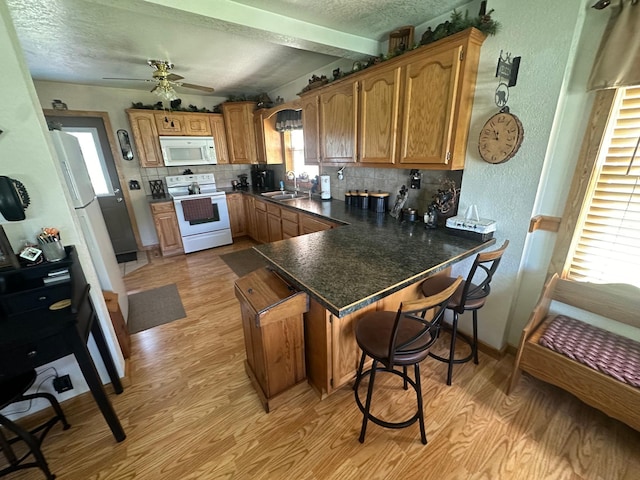310 7th Ave NE, Roseau, MN 56751 - kitchen with white appliances, light wood finished floors, a peninsula, tasteful backsplash, and a sink