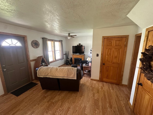 310 7th Ave NE, Roseau, MN 56751 - living room with a textured ceiling, light wood-type flooring, a fireplace, and a ceiling fan