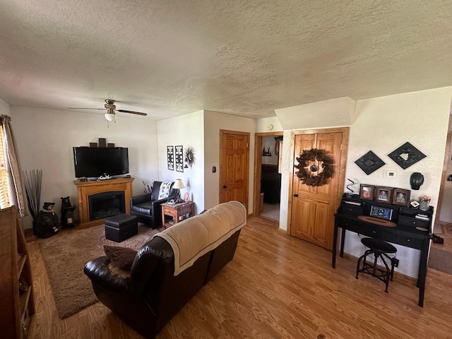 310 7th Ave NE, Roseau, MN 56751 - living area with wood finished floors, a textured ceiling, a fireplace, and ceiling fan