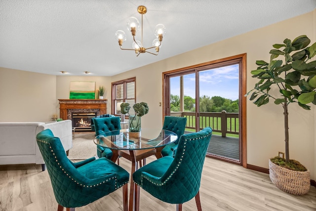 4277 Oakmede Ln Unit 62C, White Bear Twp, MN 55110 - dining area with a chandelier, light wood-type flooring, a fireplace, a textured ceiling, and baseboards