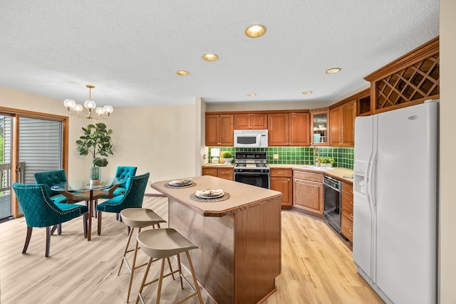 4277 Oakmede Ln Unit 62C, White Bear Twp, MN 55110 - kitchen featuring white appliances, brown cabinetry, light countertops, decorative backsplash, and light wood-style flooring