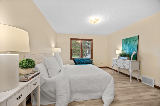 4277 Oakmede Ln Unit 62C, White Bear Twp, MN 55110 - bedroom featuring light wood finished floors, baseboards, and a textured ceiling