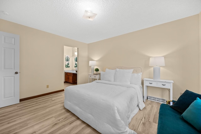 4277 Oakmede Ln Unit 62C, White Bear Twp, MN 55110 - bedroom featuring light wood-style floors, a textured ceiling, baseboards, and ensuite bathroom