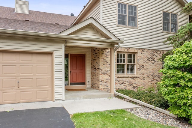 4277 Oakmede Ln Unit 62C, White Bear Twp, MN 55110 - doorway to property featuring brick siding, a garage, driveway, and a chimney