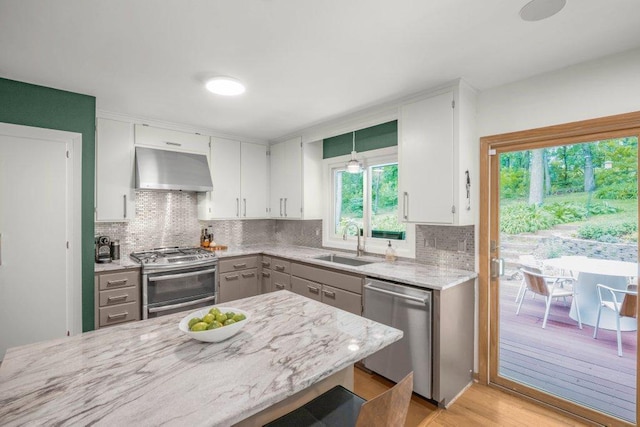 4744 Westgate Rd, Minnetonka, MN 55345 - kitchen with wall chimney range hood, appliances with stainless steel finishes, backsplash, and white cabinetry