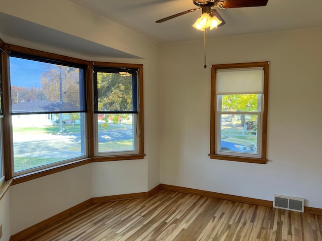 spare room featuring light wood finished floors, baseboards, ceiling fan, and ornamental molding