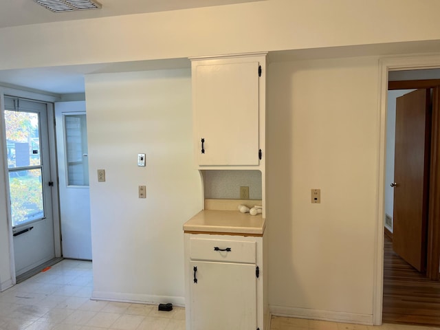 kitchen featuring light countertops, white cabinets, baseboards, and light floors
