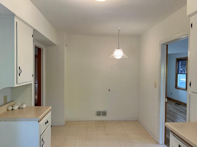 kitchen with light countertops, white cabinets, light floors, pendant lighting, and baseboards