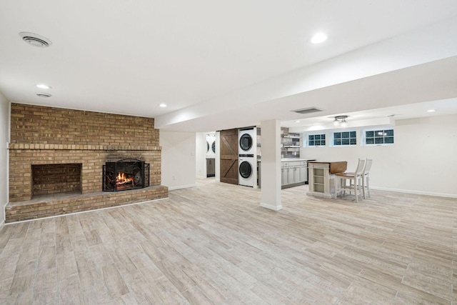 5078 Vine Hill Rd, Deephaven, MN 55331 - unfurnished living room featuring stacked washer / dryer, a fireplace, light wood finished floors, baseboards, and recessed lighting