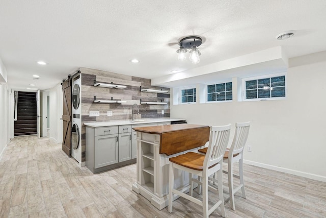 5078 Vine Hill Rd, Deephaven, MN 55331 - kitchen featuring open shelves, stacked washing machine and dryer, gray cabinets, light wood-style floors, and baseboards