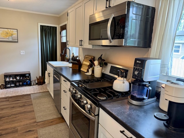 2728 Pine Ave, Slayton, MN 56172 - kitchen with appliances with stainless steel finishes, a sink, dark countertops, ornamental molding, and dark wood-type flooring